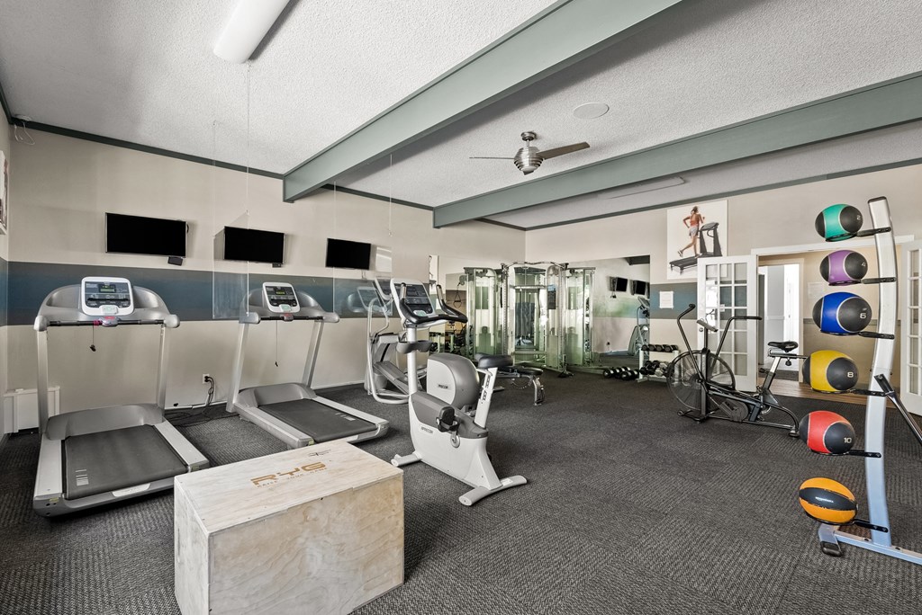 a gym with treadmills and weights and a table