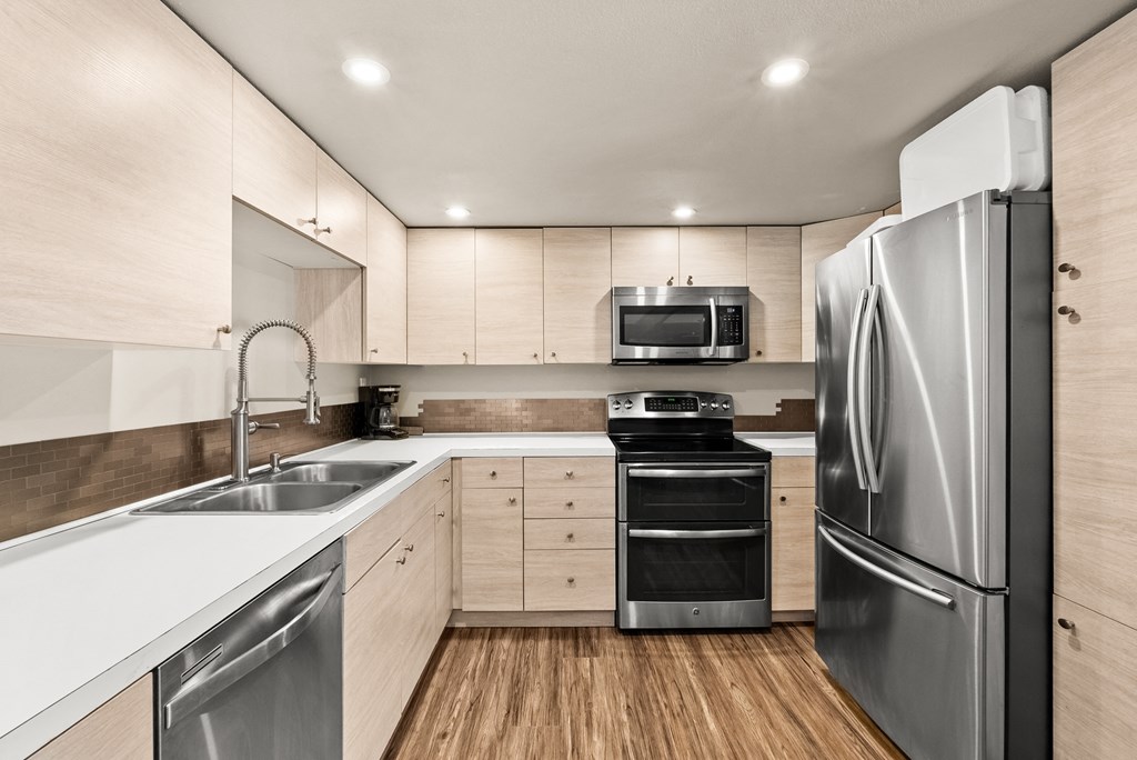 a modern kitchen with stainless steel appliances and white counter tops