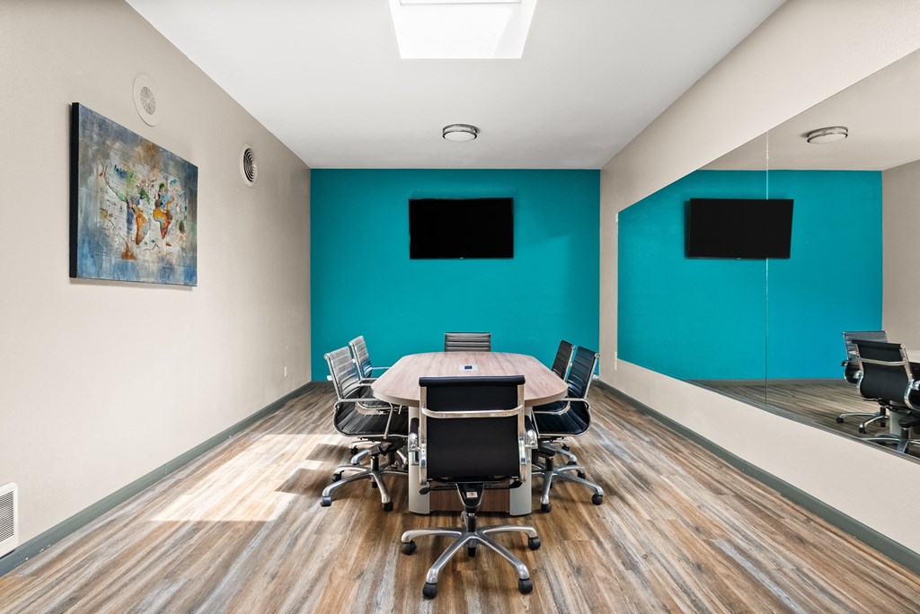 a conference room with a table and chairs and two televisions
