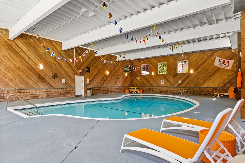 a swimming pool in a building with wooden walls and a ceiling