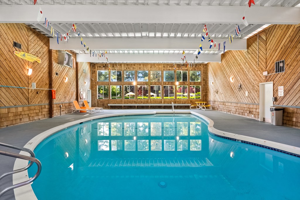 a swimming pool in a room with wooden walls and a large window