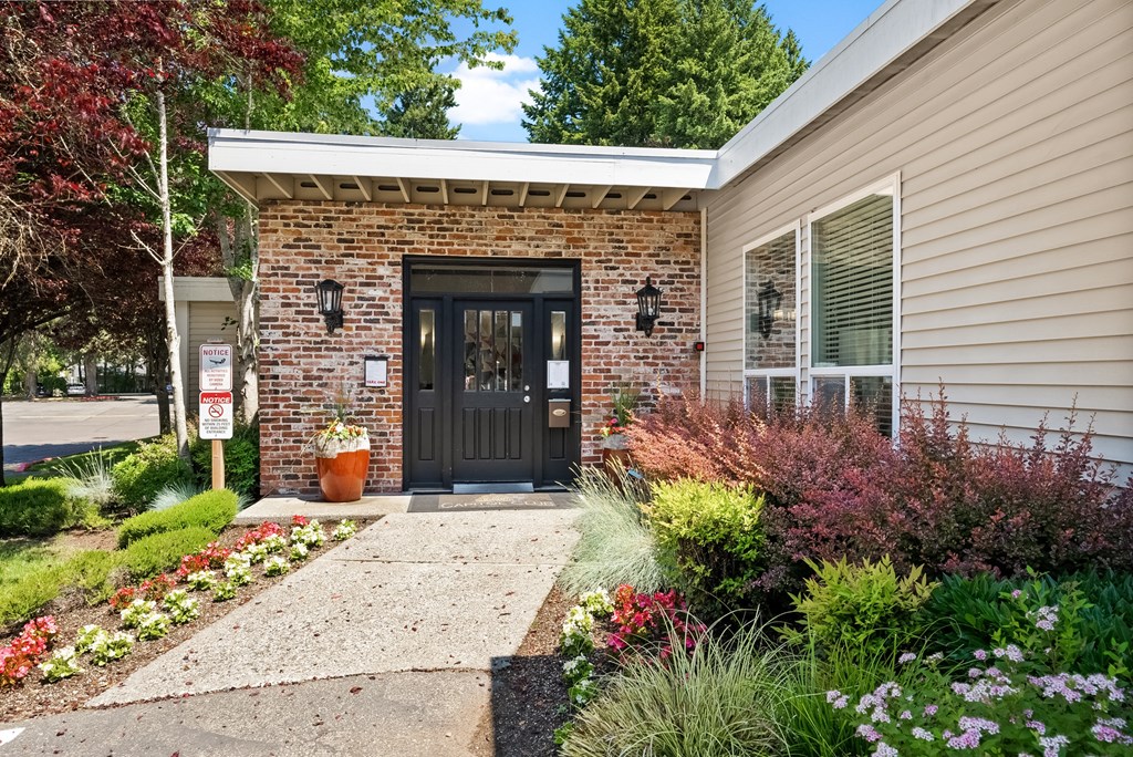 the front door of a home with a sidewalk and landscaping