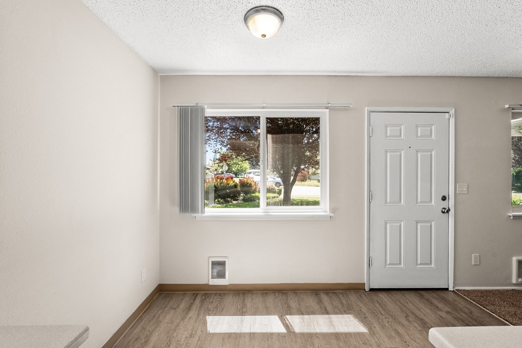 an empty living room with a window and a white door