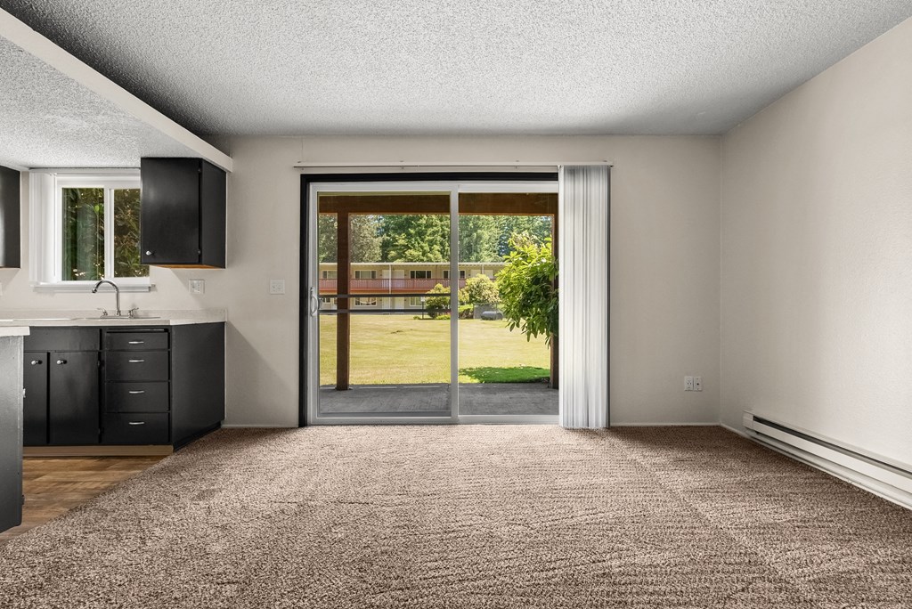 an empty living room with sliding glass doors to a yard