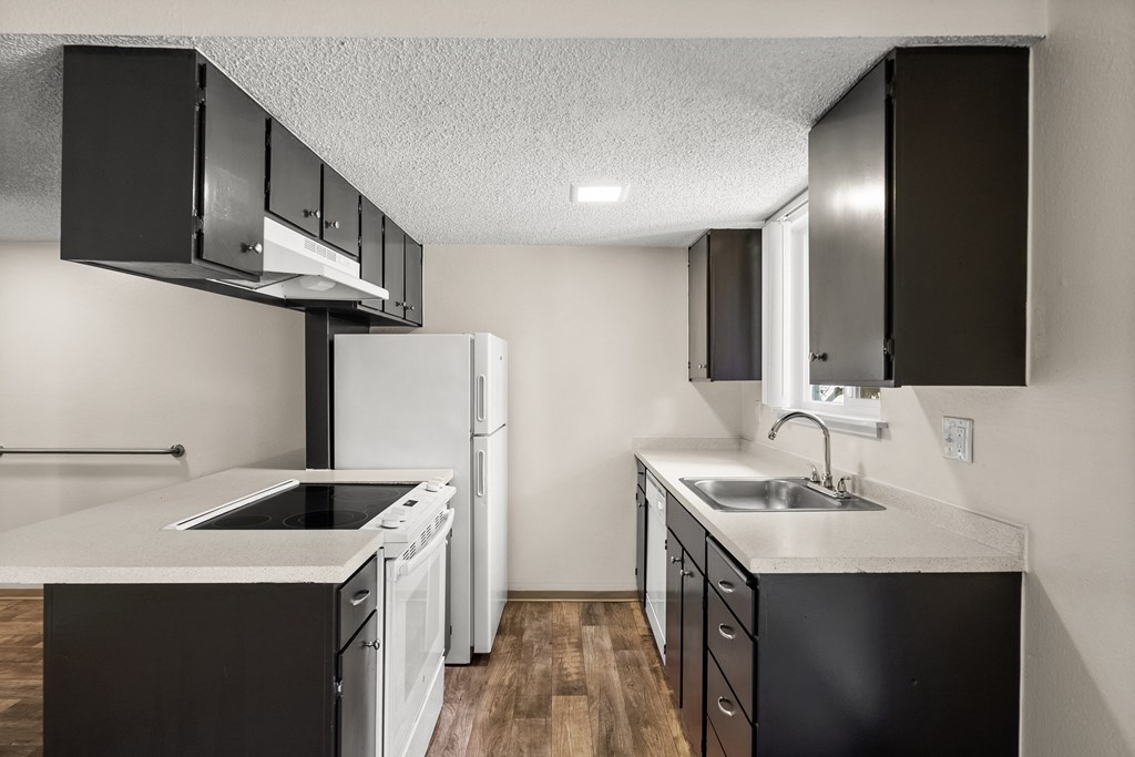 an empty kitchen with white appliances and black cabinets