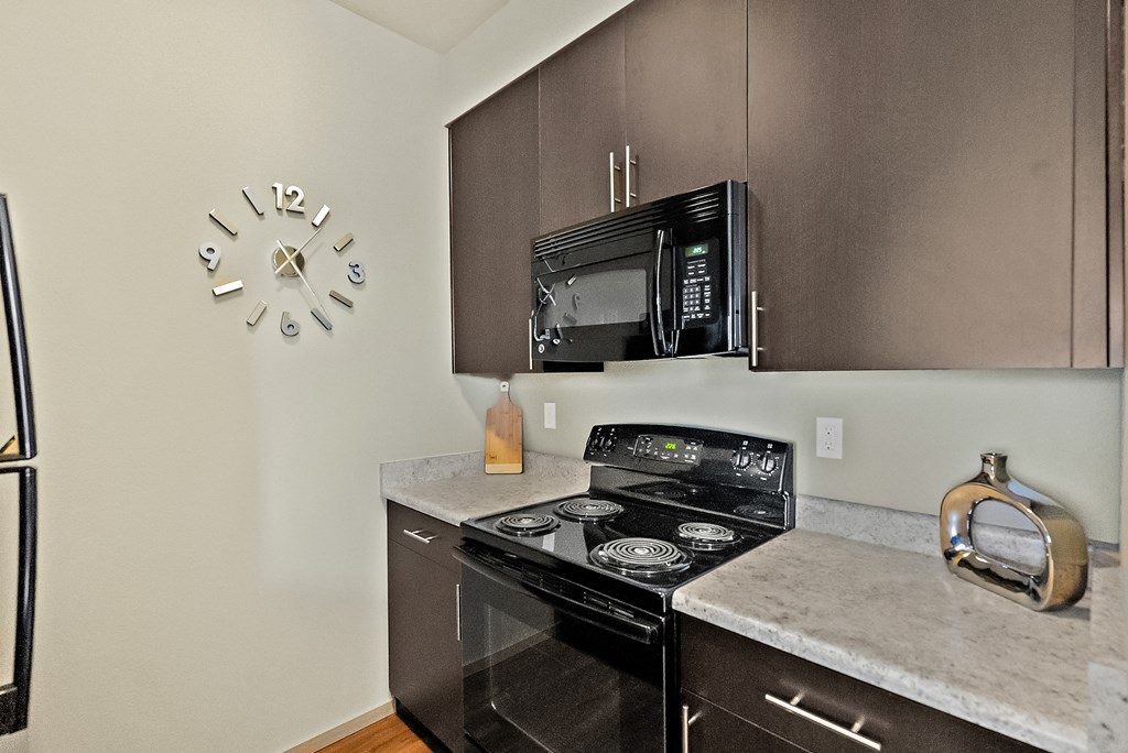a kitchen with a stove and microwave and a clock on the wall