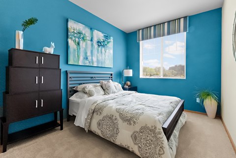 a bedroom with a bed and blue walls and a window