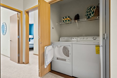 a washer and dryer in a laundry room with a door to a bedroom