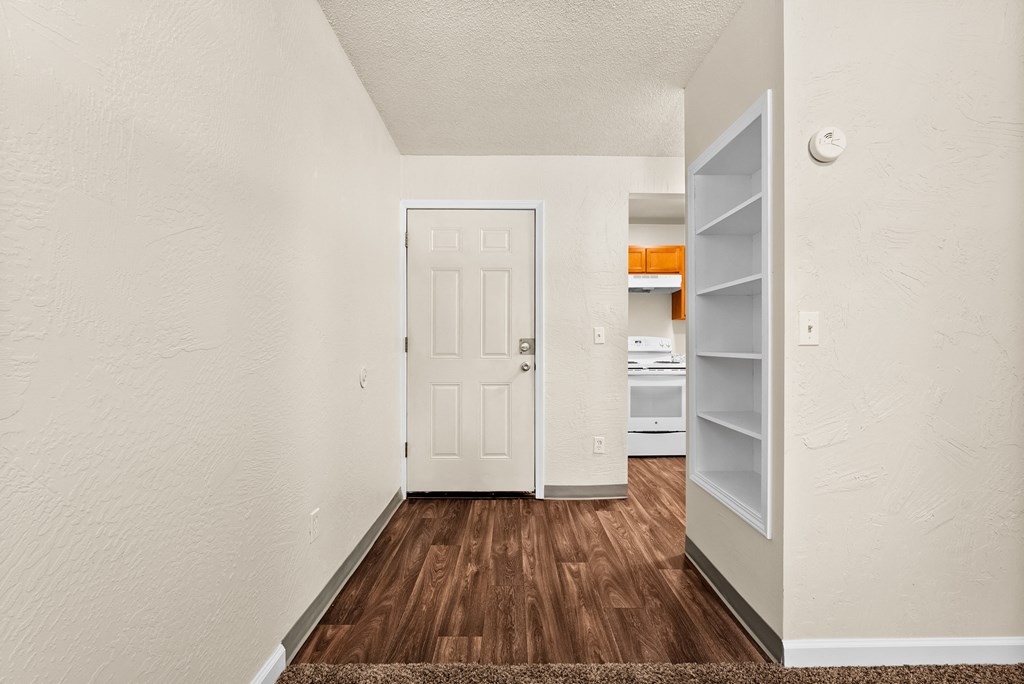 a renovated living room with a white door and a kitchen