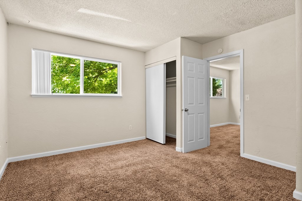 an empty bedroom with a closet and a window