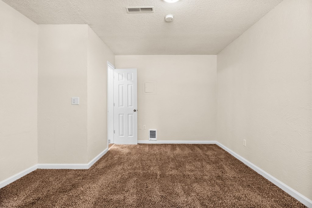 an empty living room with carpet and a white door