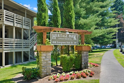 a sign for heritage park apartments in front of a sidewalk