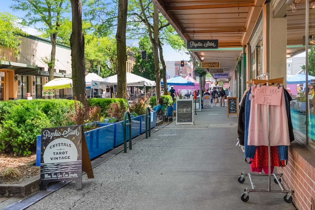 a city street with shops and pedestrians on a sidewalk
