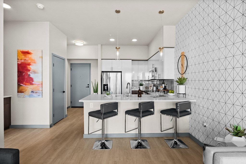 an open kitchen with an island and three stools in front of a white counter