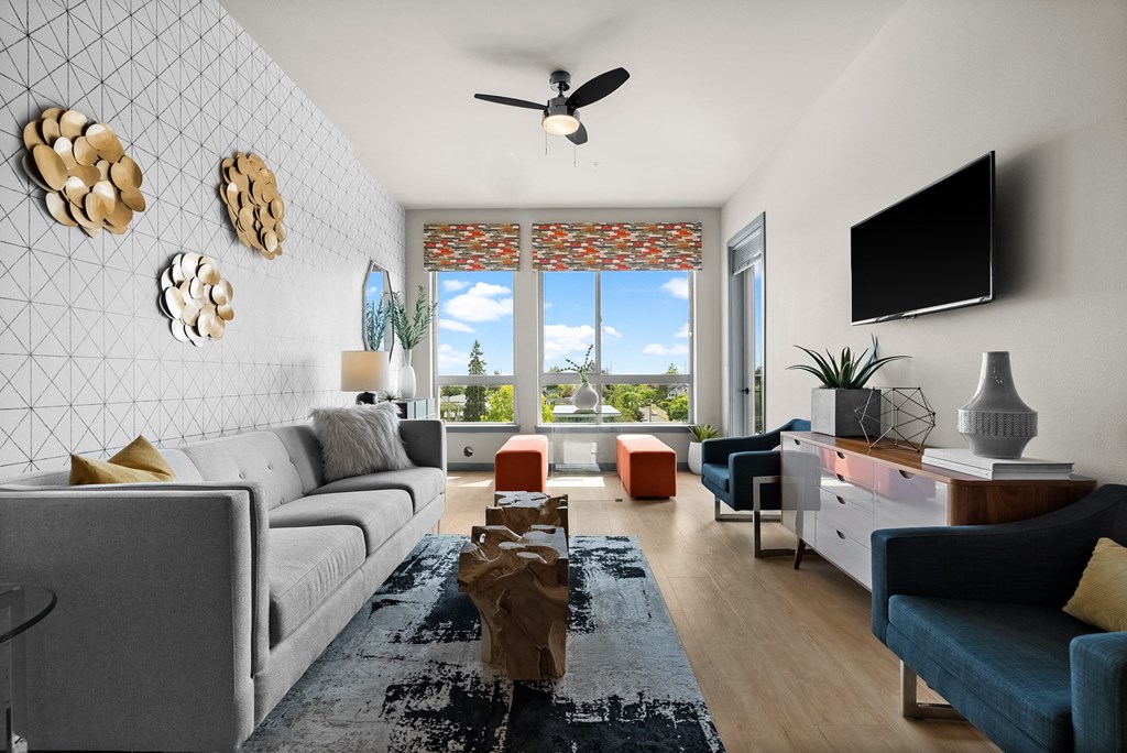 a living room with a large window and a ceiling fan