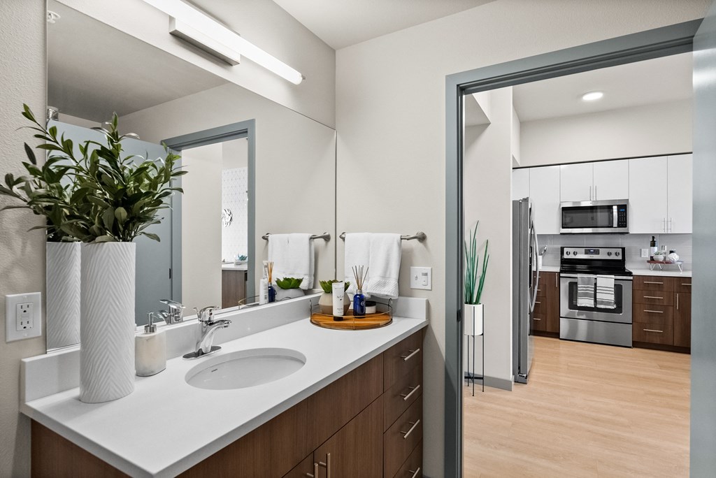 a kitchen with white counters and a sink and a mirror