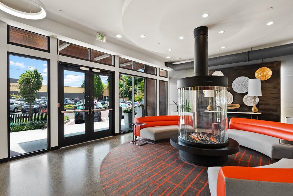 the lobby of a hotel with a fireplace and orange chairs