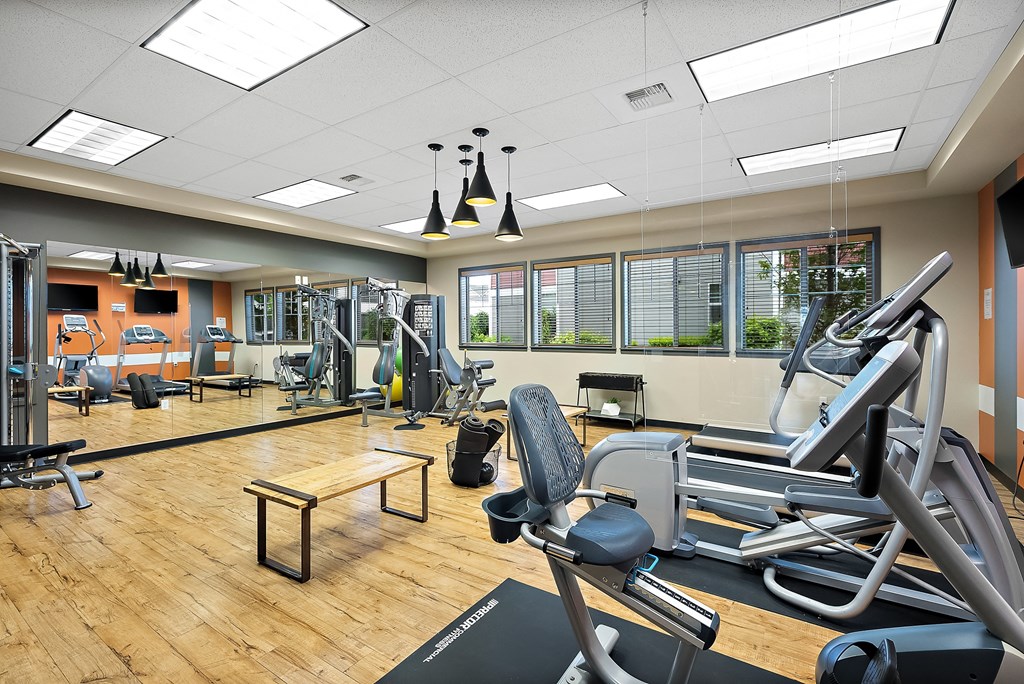 a gym with cardio machines and weights on a wooden floor