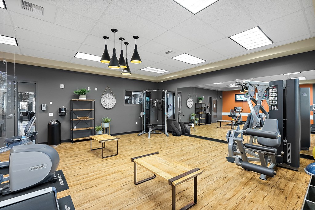 a gym with cardio machines and weights on a wooden floor