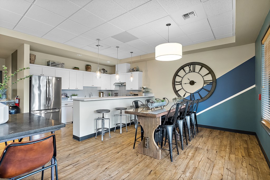 a kitchen with a large clock on the wall and a table with chairs