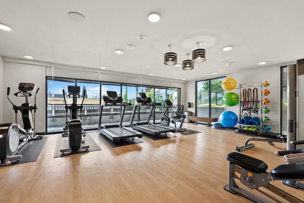 a gym with cardio equipment and views of the gym floor and windows