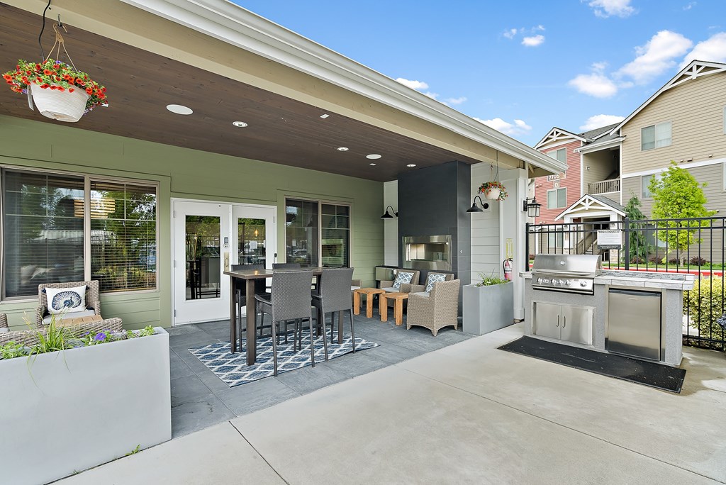 a patio with a grill and a table with chairs