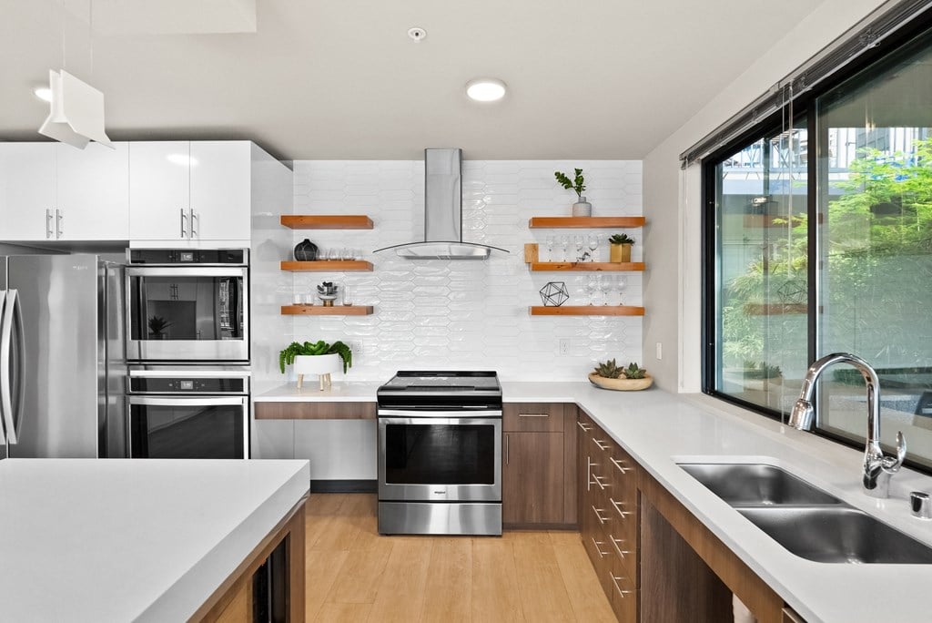 a kitchen with white counters and stainless steel appliances and a large window