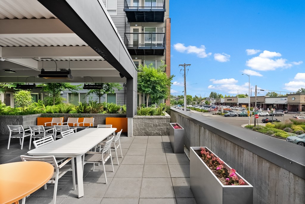 an outdoor patio with tables and chairs and a building in the background