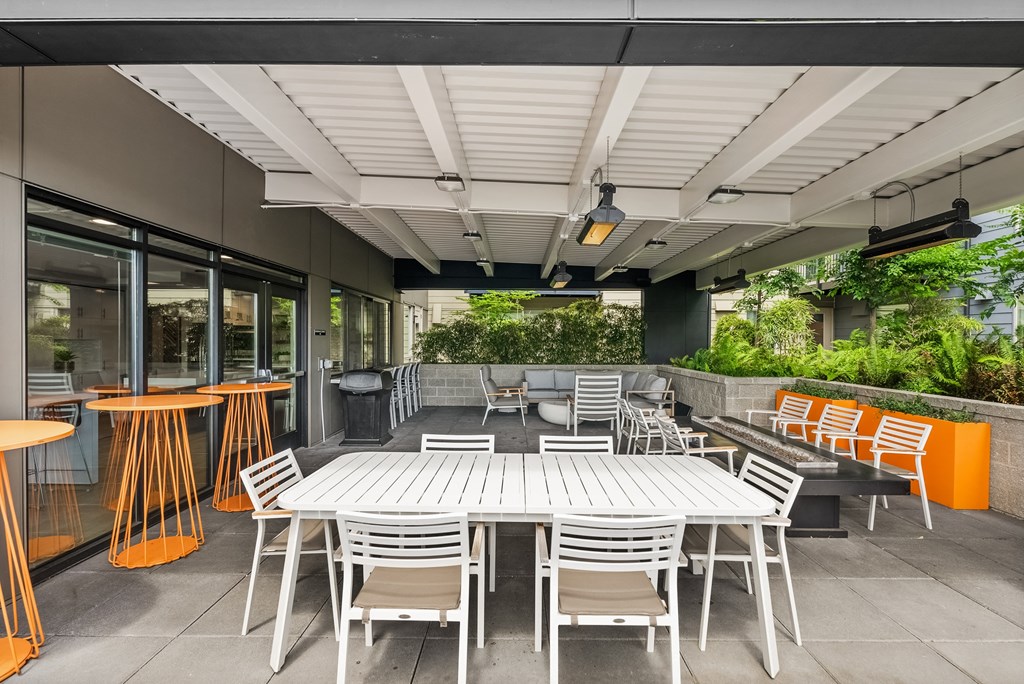 an outdoor patio with white tables and chairs and orange chairs