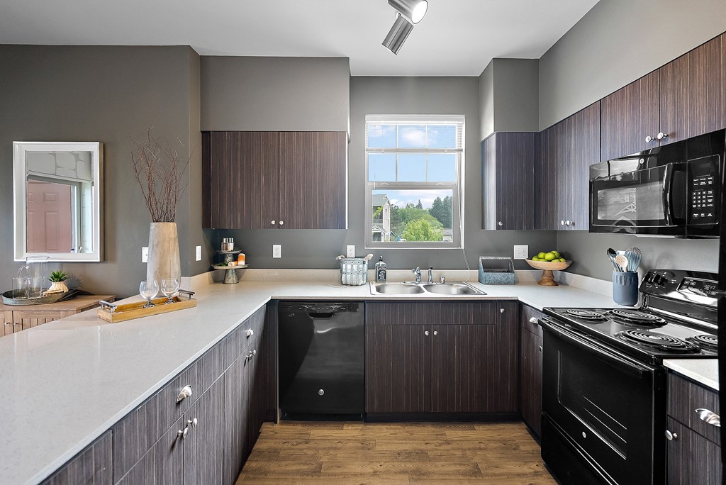 an updated kitchen with black appliances and white countertops