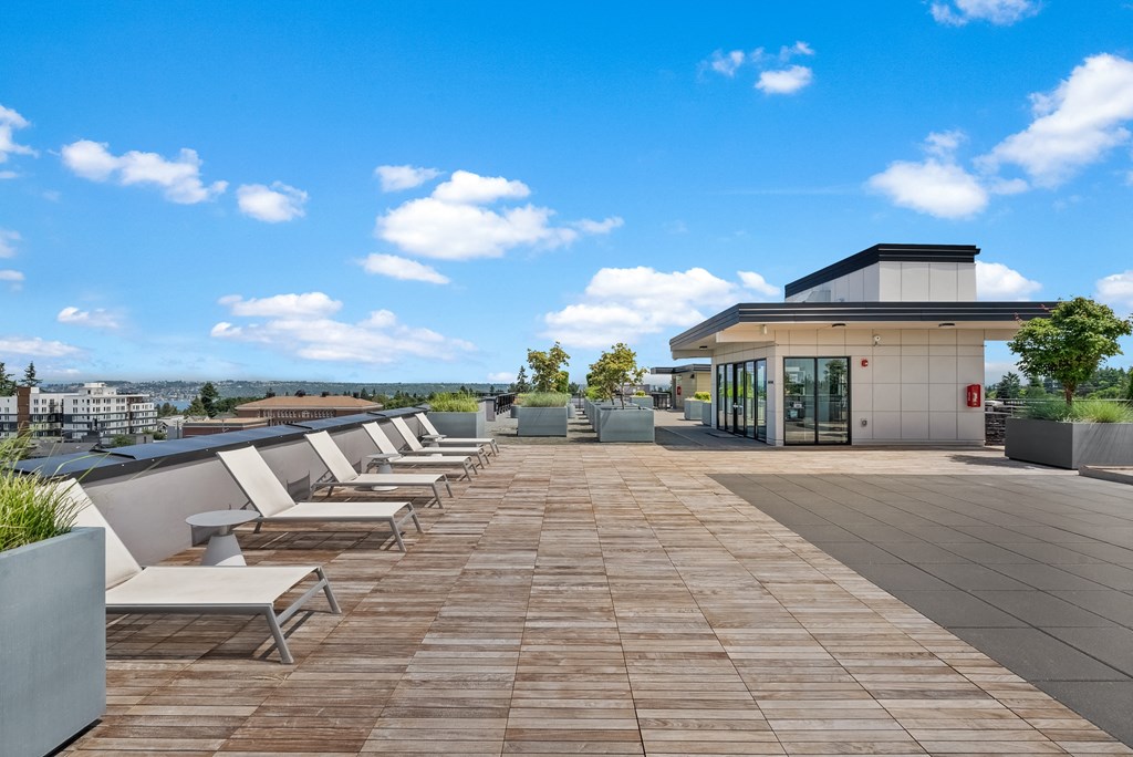 a roof deck with lounge chairs and a building