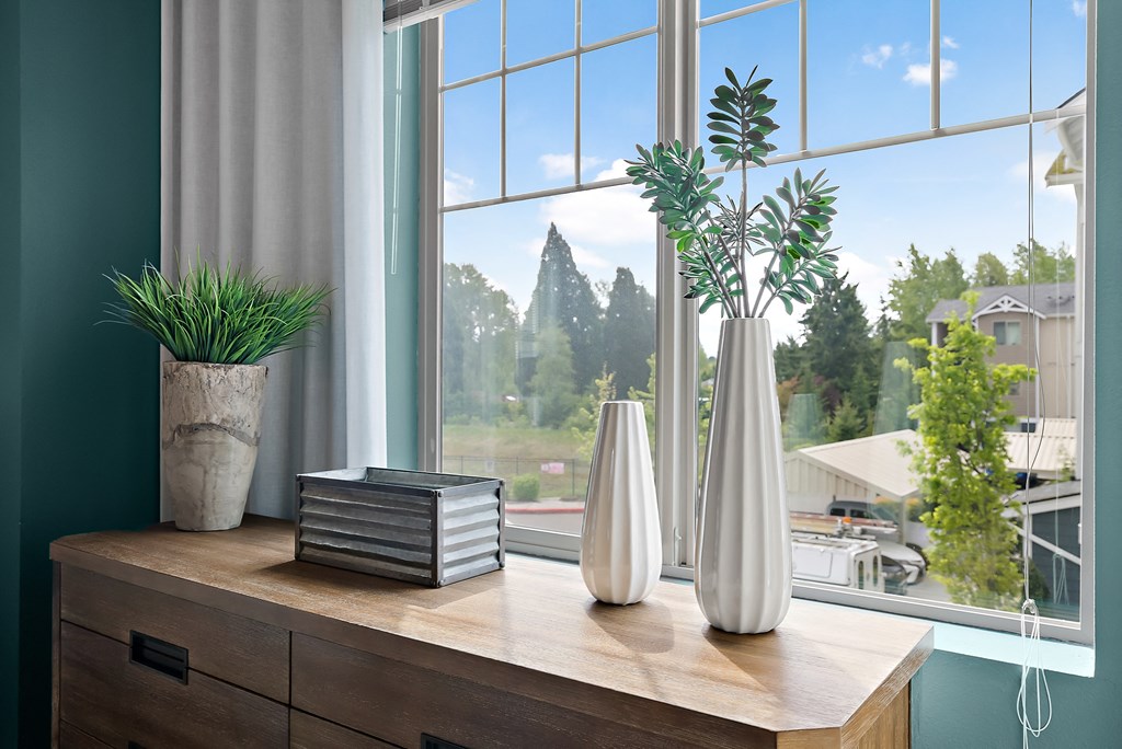a wooden table with vases and plants in front of a window