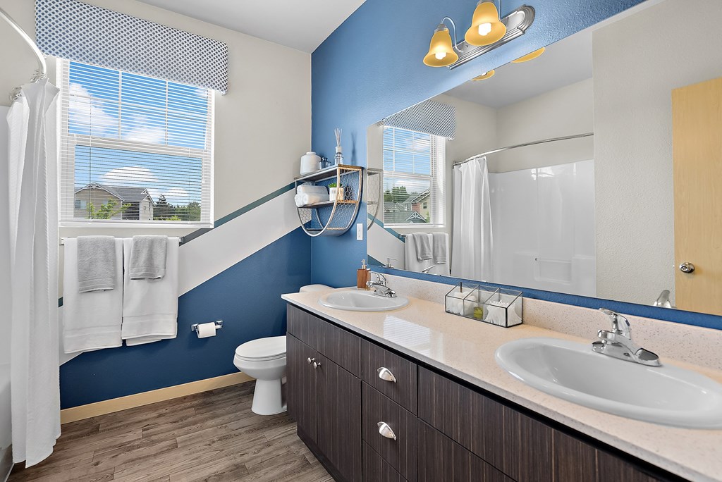 a bathroom with two sinks and a toilet and a shower