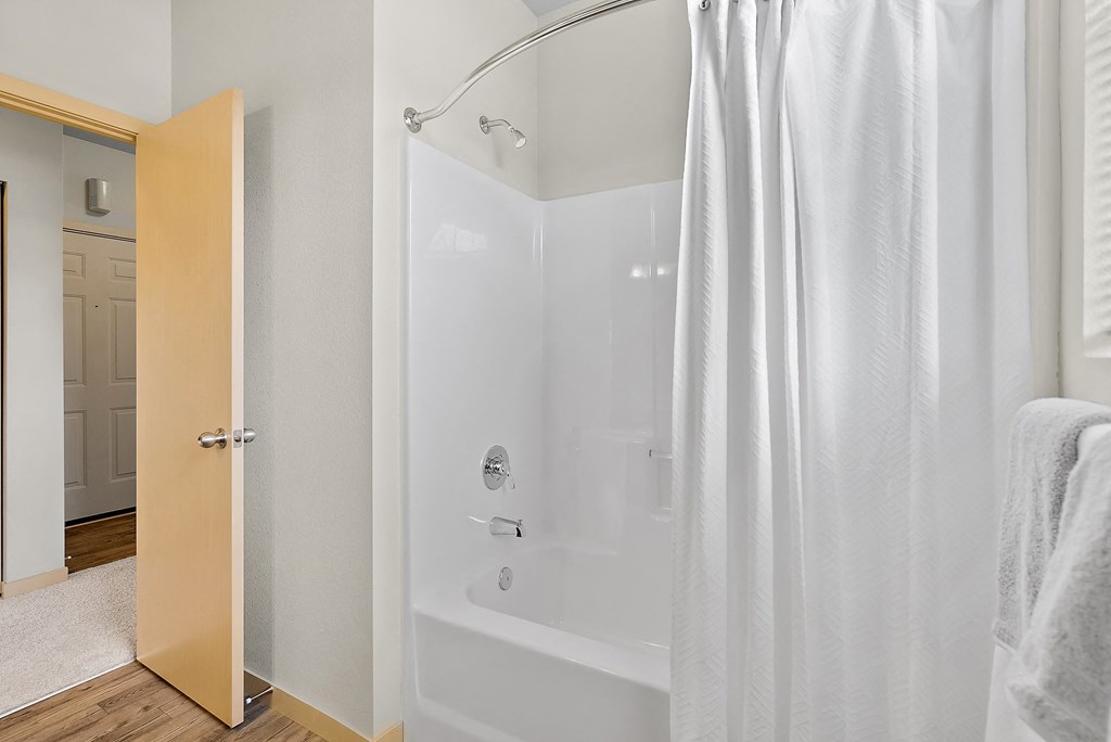 a bathroom with a white shower and a white curtain