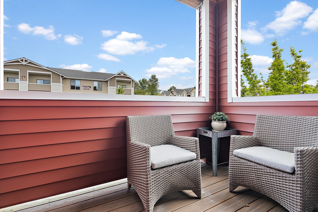 a porch with two chairs and a view of a house
