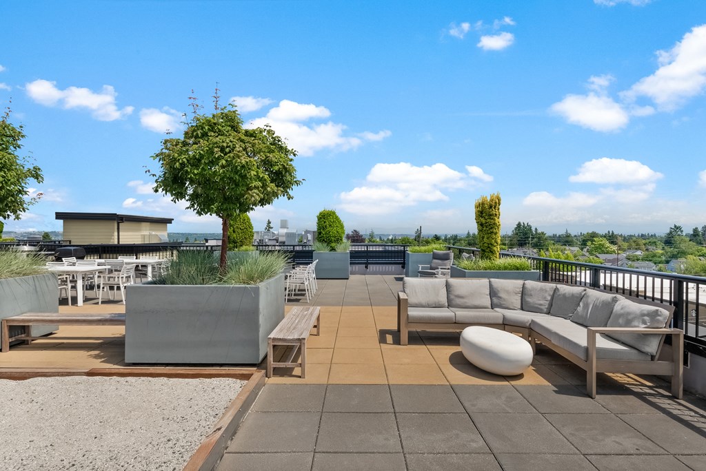 a roof top patio with couches and tables and views of the city