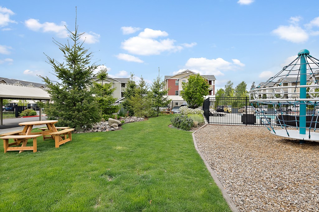 a park with a playground and picnic table on the grass