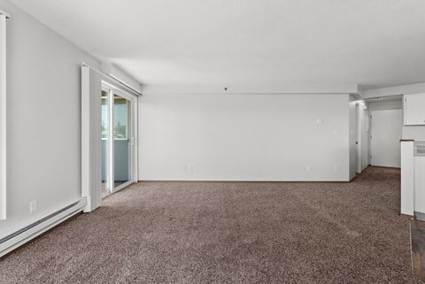 the living room of an apartment with carpet and white walls