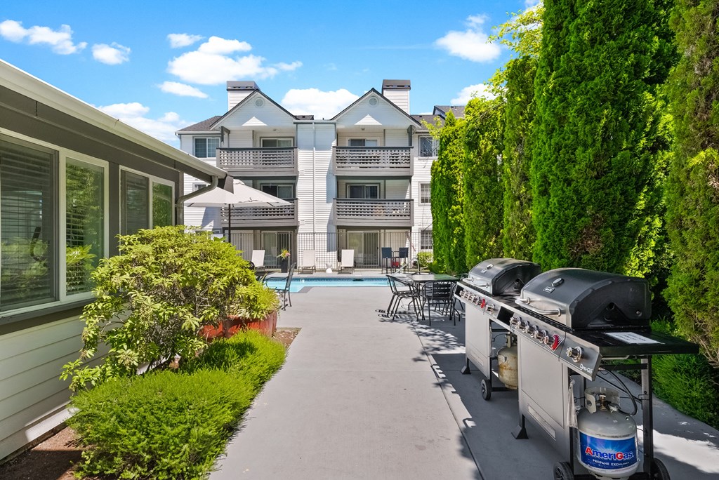 a patio with a grill and a pool in front of a house