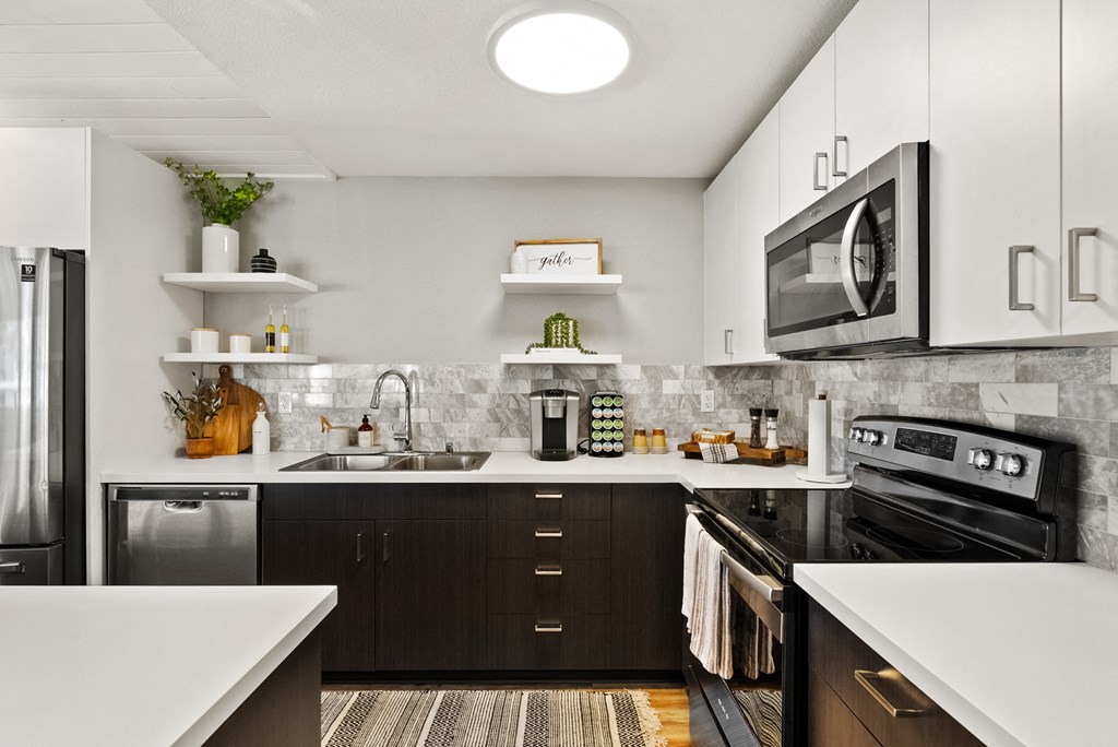 a kitchen with black appliances and white cabinets and a stainless steel refrigerator