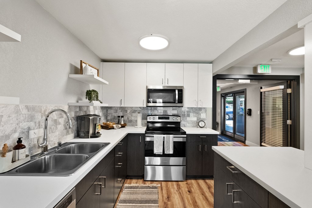 an open kitchen with white counter tops and black and white appliances