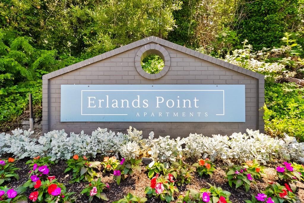 a sign that says rentals point apartments in a garden with flowers