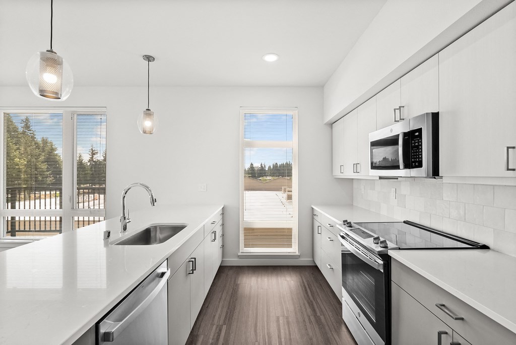 a kitchen with white countertops and stainless steel appliances
