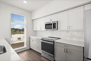 A modern kitchen with white cabinets and stainless steel appliances.