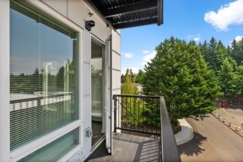 A balcony with a view of a parking lot and trees.
