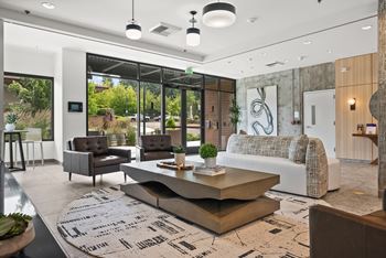 A modern living room with a large rug and a coffee table in the center.