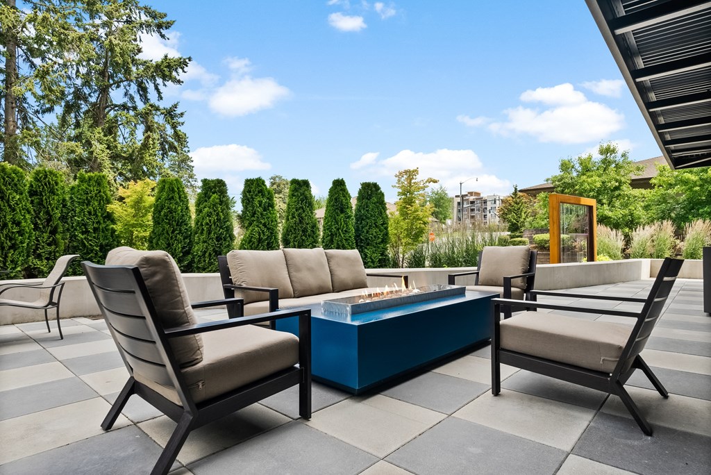 a patio with chairs and a table with a fire pit in the middle of it