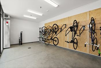 A room with a wall of bicycles and a door on the left.