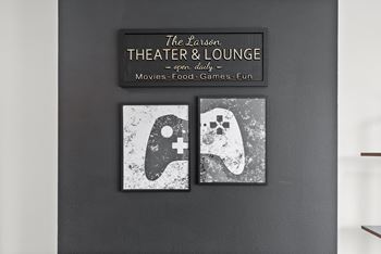 A wall with a sign that says "The Larson THEATER & LOUNGE" and two pictures of a video game controller and a ghost.