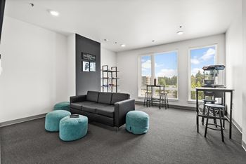 A black couch with a blue ottoman in front of a window.